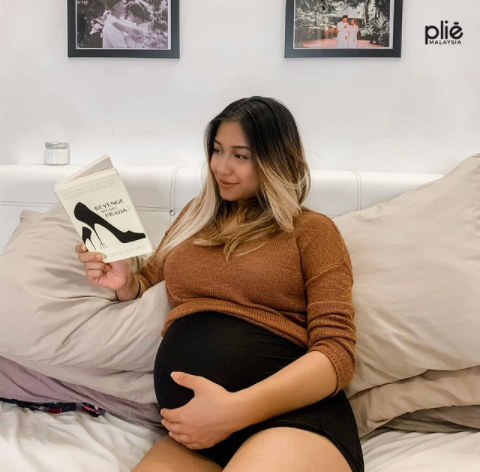 Pliemum reading book and wearing Maternity high waist shorts.